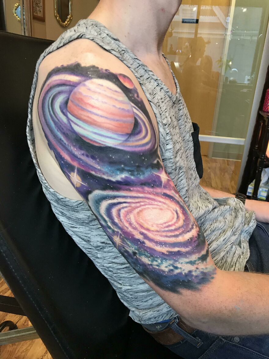 Arm tattoo featuring a colorful space design with planets and galaxies, embodying outer space cool.