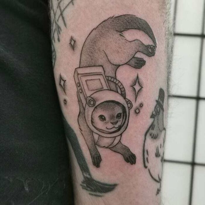 Space tattoo of an otter in an astronaut suit on a person's arm.