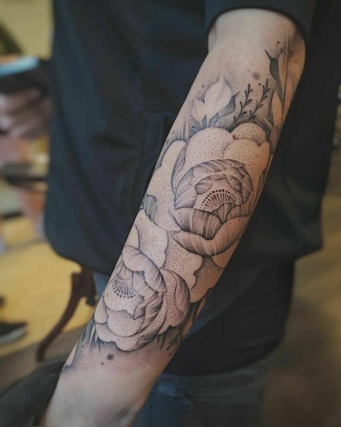 Arm with intricate flower tattoos, showcasing detailed blossom design.
