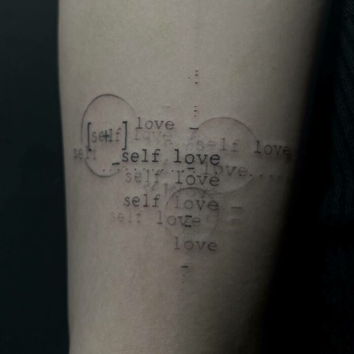 Self-love tattoo with layered text design on forearm, promoting inspiration and empowerment through personal meaning.
