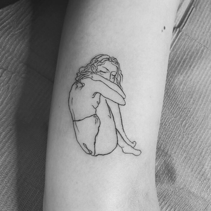Line art tattoo of a woman hugging herself, symbolizing self-love.
