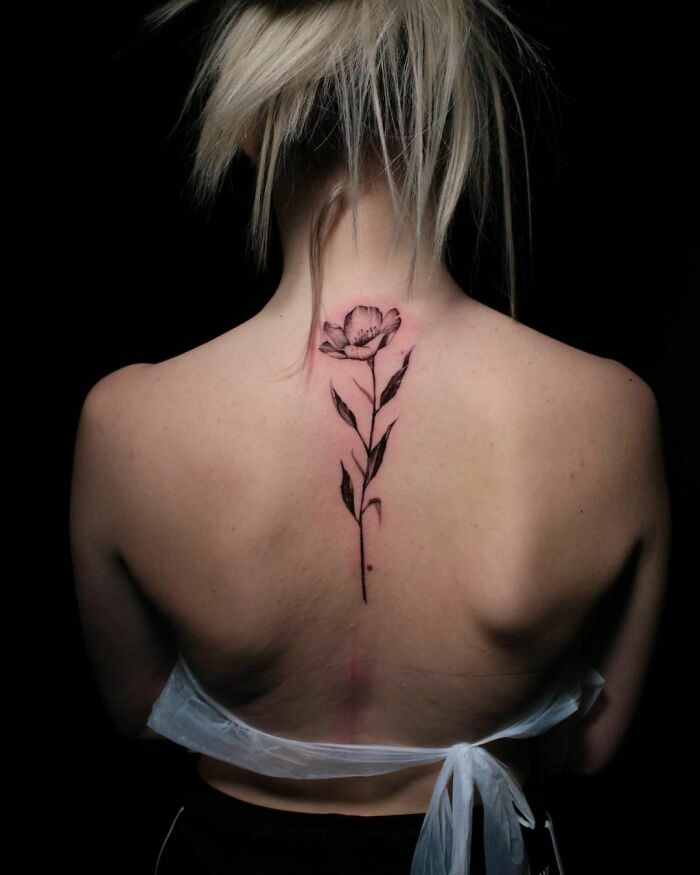Elegant flower tattoo on woman's back, showcasing beauty and intricate artistry.