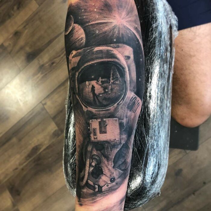 Astronaut space tattoo on arm, featuring planets and stars for astrology fans.
