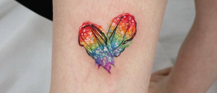 Colorful rainbow heart tattoo symbolizing self-love on skin.