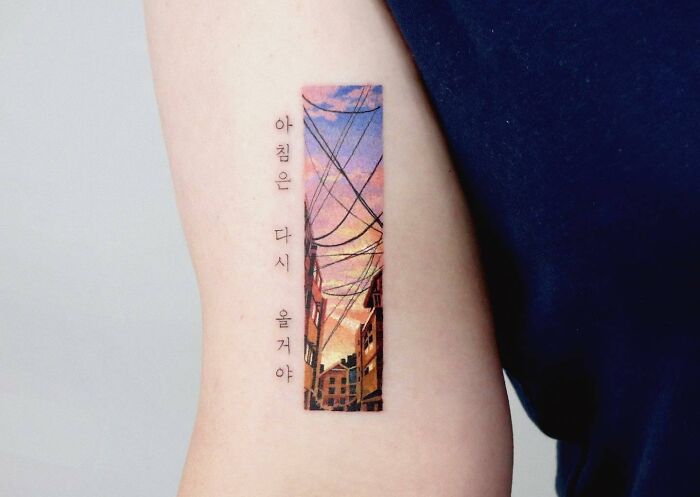 City sunrise tattoo on arm symbolizing self-love.