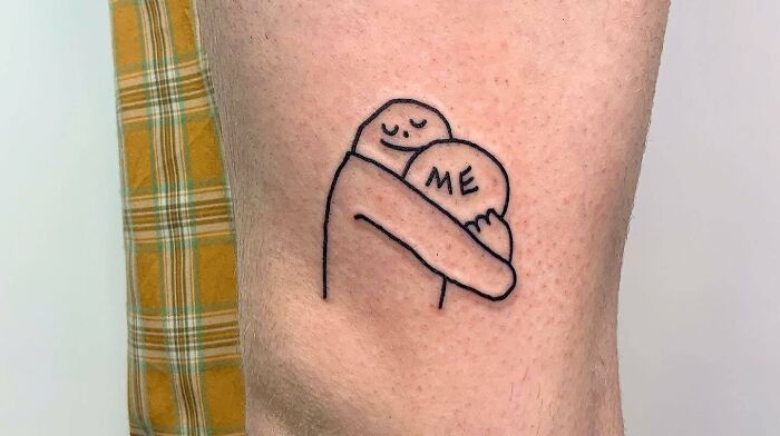 Minimalist self-love tattoo of a hugging figure with "ME" on the arm, symbolizing self-embrace and empowerment.