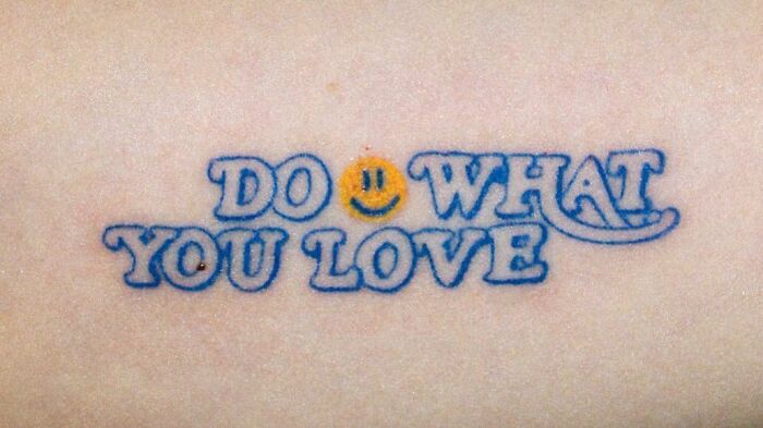 Self-love tattoo saying "Do What You Love" with a smiley face, celebrating personal importance.