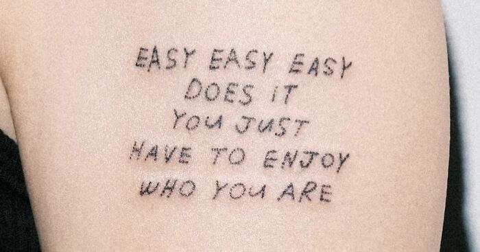 Tattoo saying "You Just Have To Enjoy Who You Are" celebrating self-love on skin.