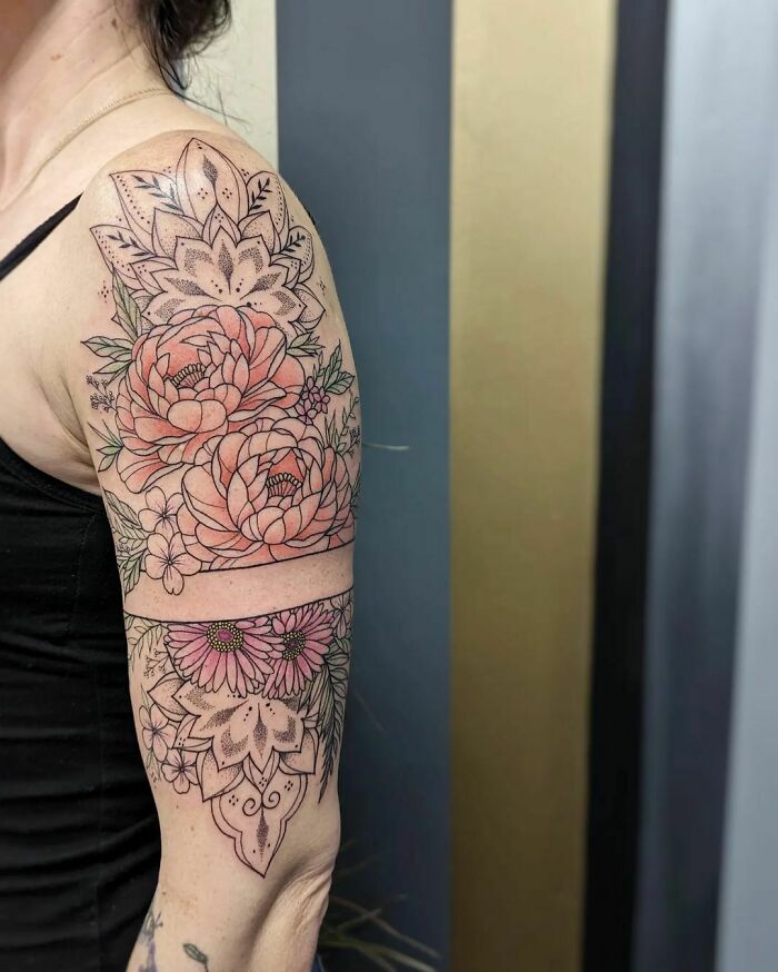 Floral arm tattoo with detailed blossoms and leaves, showcasing vibrant flower design on the skin.