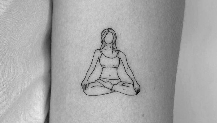 Minimalist self-love tattoo of a faceless woman in a meditative pose on forearm.