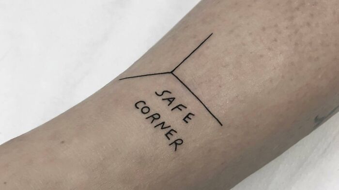 Minimalist self-love tattoo with "Safe Corner" text on forearm.