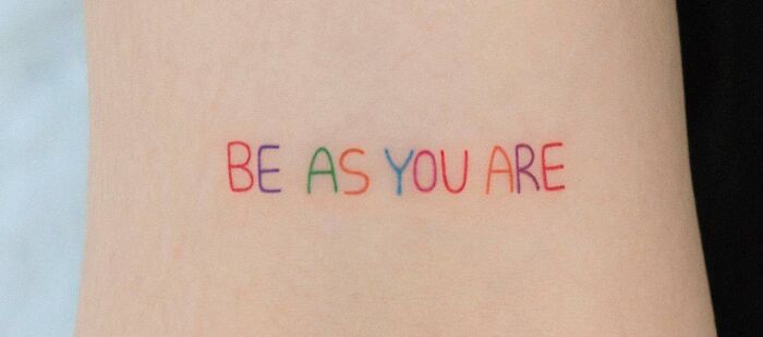 "Be As You Are" self-love tattoo in colorful ink on skin.