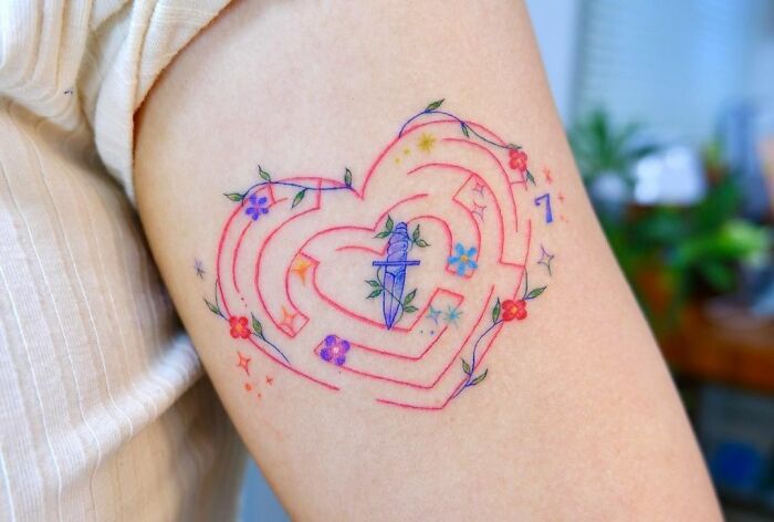 Colorful self-love tattoo with a heart design and floral details on an arm, symbolizing empowerment and inspiration.
