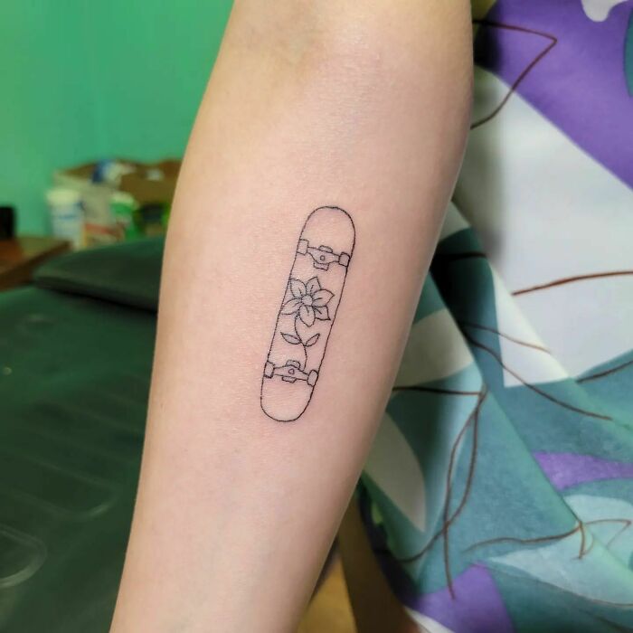 Minimalist flower tattoo on forearm, blending elegance with skate-inspired design.