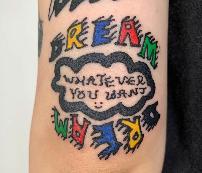 Colorful self-love tattoo with the words "Dream Whatever You Want" in a playful, artistic font.