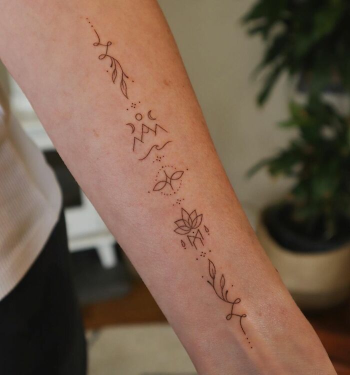 Self-love tattoo featuring leaves and mountains on a person's forearm.
