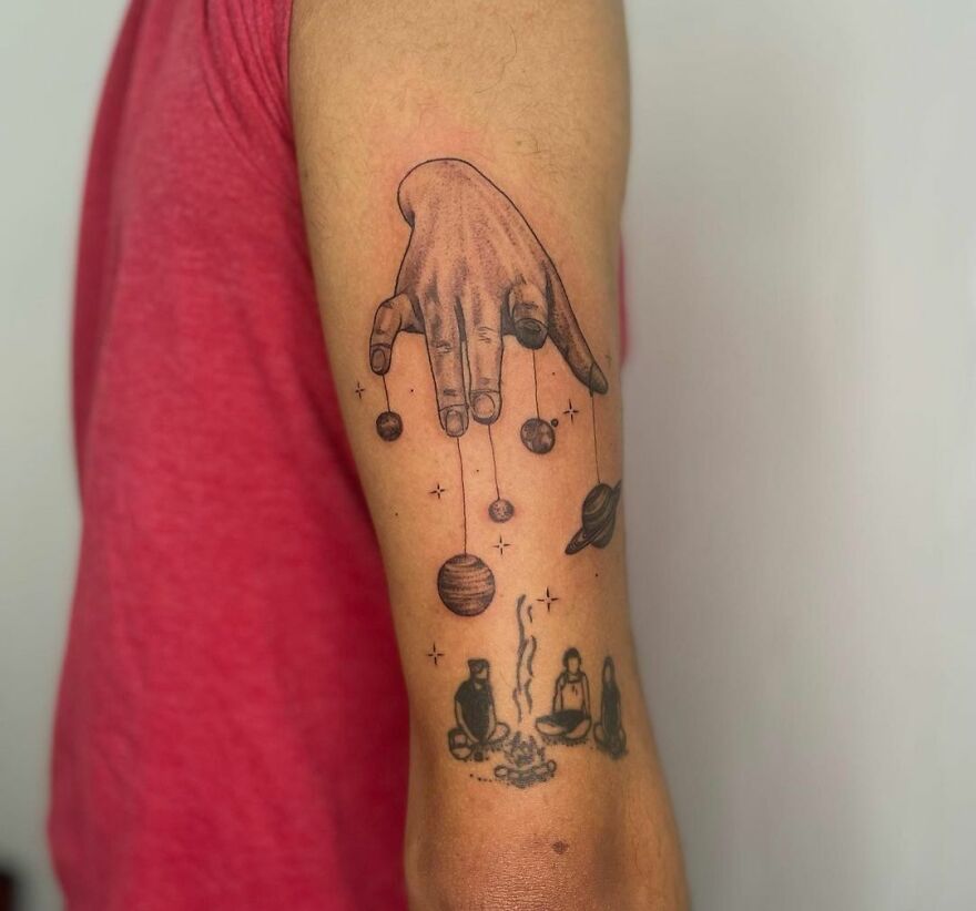 Astrology tattoo of a hand controlling planets on an arm, with celestial and spiritual symbols.