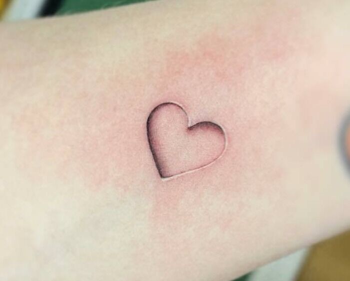 Heart-shaped self-love tattoo on skin, showcasing minimalist and meaningful design.