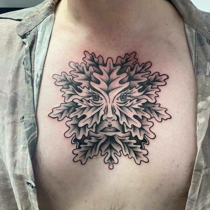 Chest tattoo of an intricate leafy face design symbolizing self-love and empowerment.