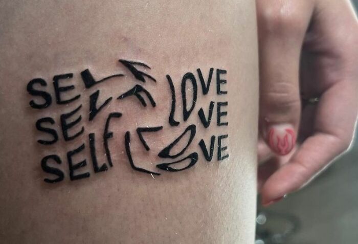 Self-love tattoo with artistic text design on a person's arm.