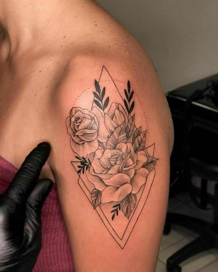 Black and grey flower tattoo with geometric shapes on upper arm.
