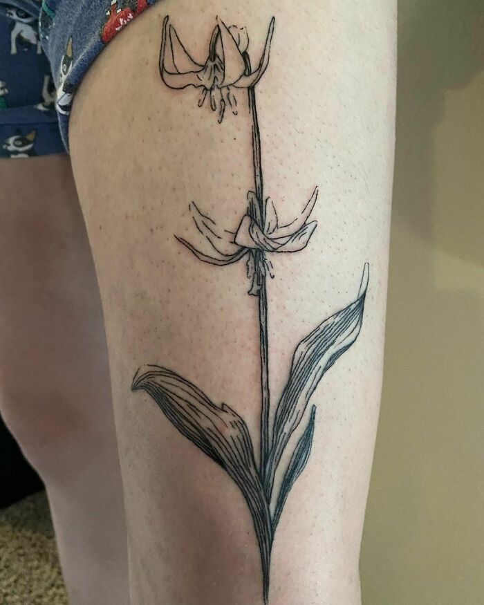 Elegant flower tattoo on thigh showcasing beauty and grace.