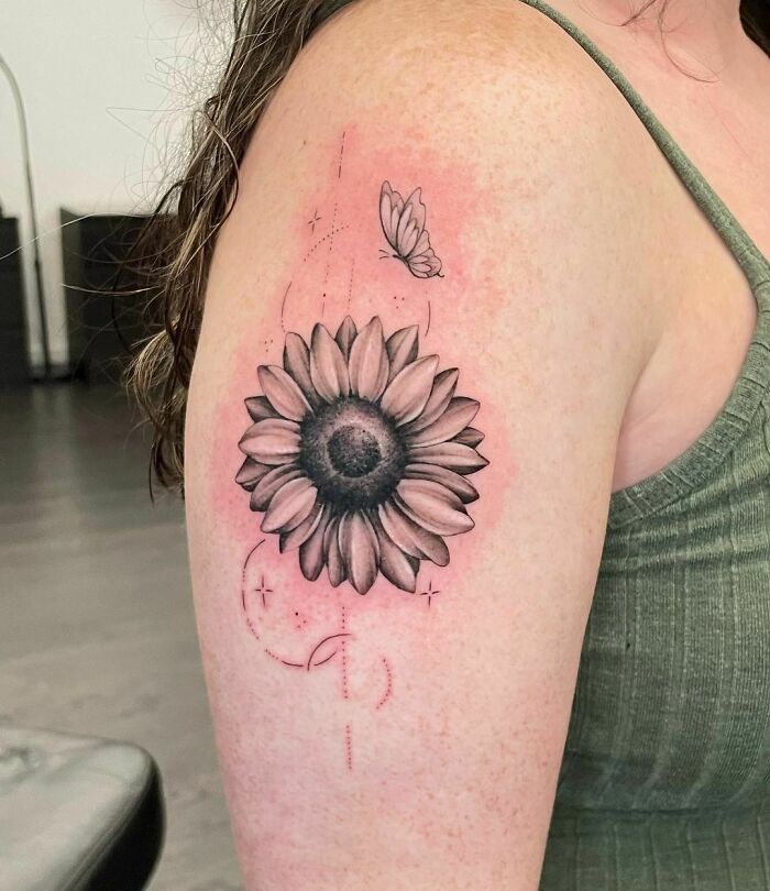Flower tattoo with sunflower and butterfly design on upper arm.