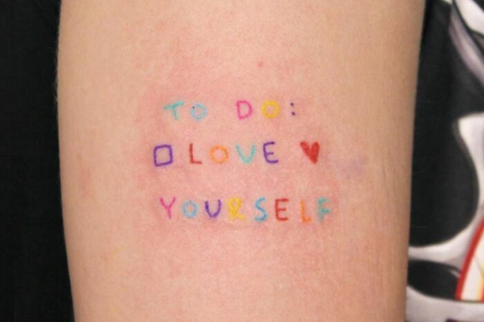 "Self-love tattoo with 'To Do: Love Yourself' inscription in colorful letters on skin."