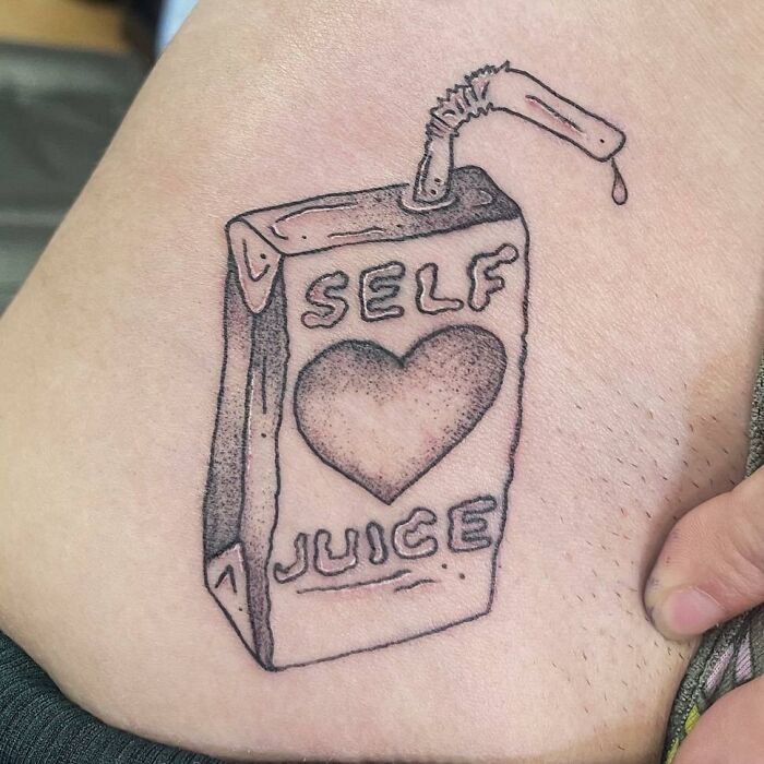 Self-love juice box tattoo with a heart design on skin, symbolizing self-care.