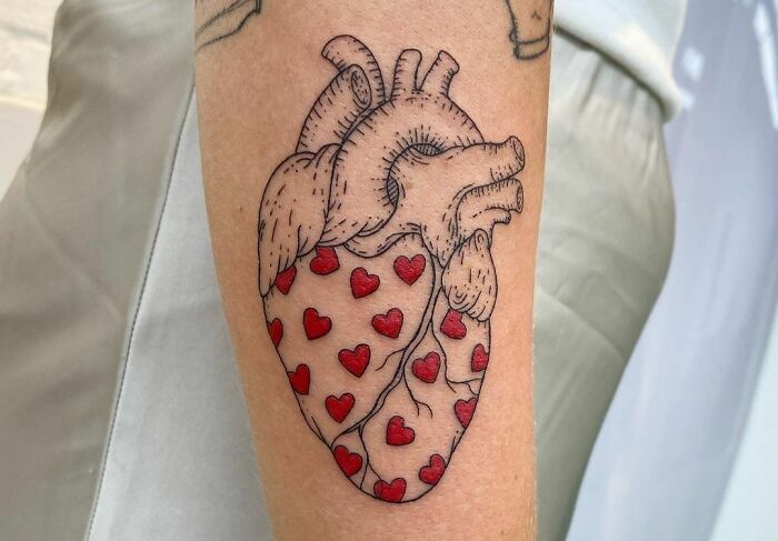 An anatomical heart tattoo with red hearts symbolizes self-love and empowerment.