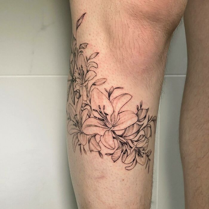 Flower tattoo on skin, showcasing detailed blossoms wrapped around a leg.
