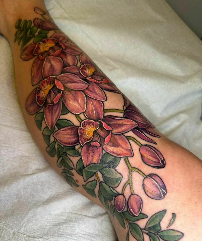 Elegant flower tattoo on arm, showcasing detailed pink and green floral design.