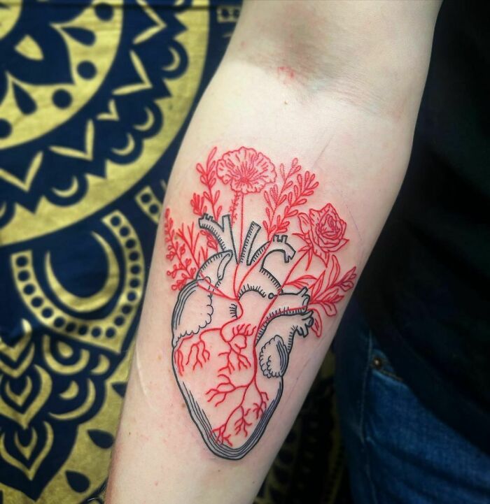 Floral heart tattoo design combining flowers and anatomical elements, showcasing elegance and beauty on the forearm.
