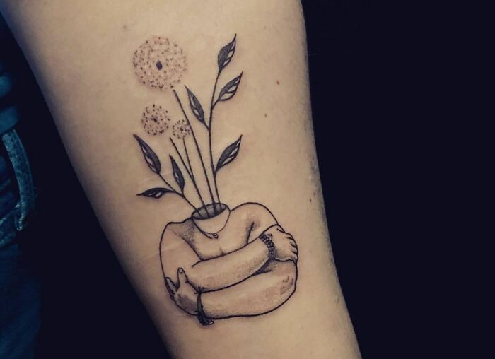 Self-love tattoo of a hugging figure with flowers growing, symbolizing growth and empowerment.