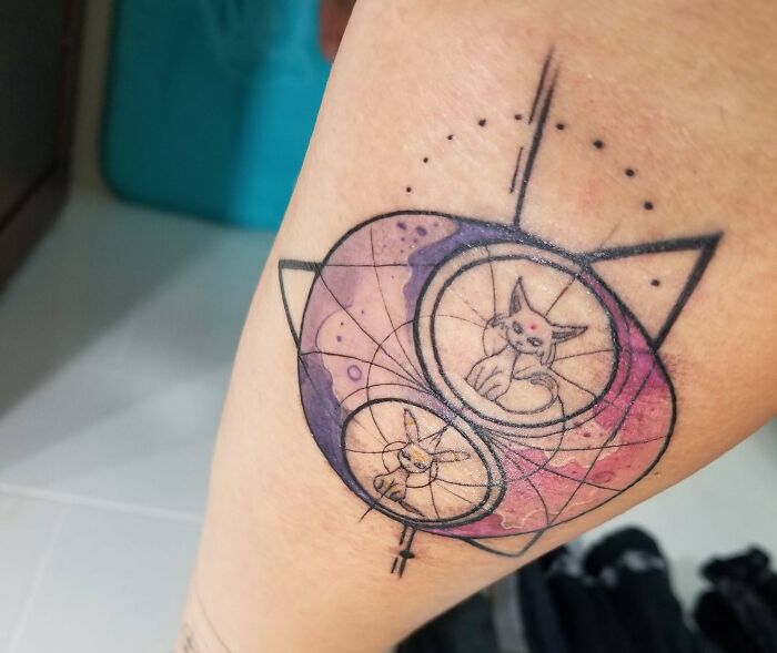 Geometric tattoo with abstract shapes and cat designs on the arm.