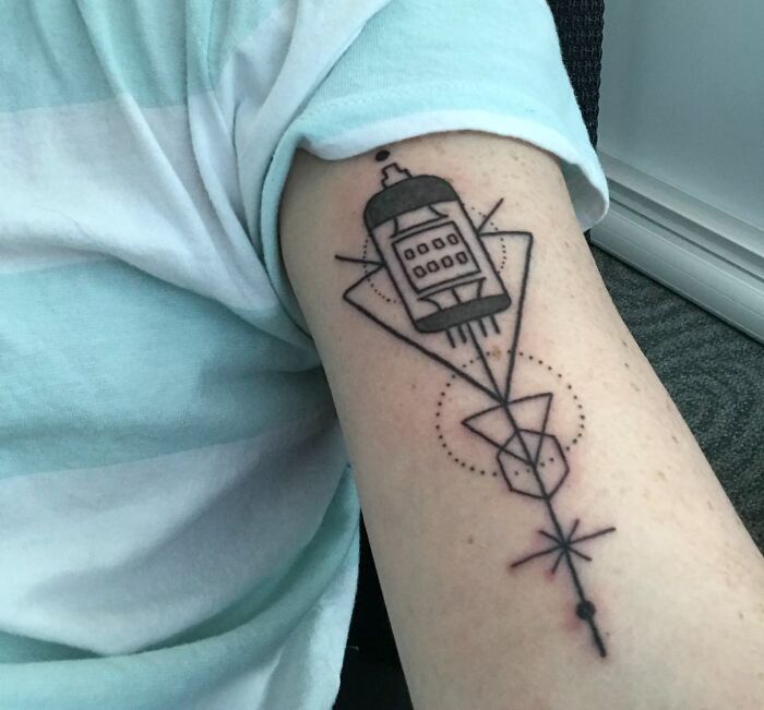 Geometric tattoo on arm with intersecting shapes and line patterns.