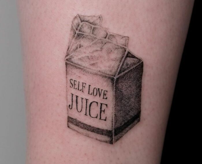 Tattoo of a juice box labeled "Self Love Juice," symbolizing self-love and empowerment.