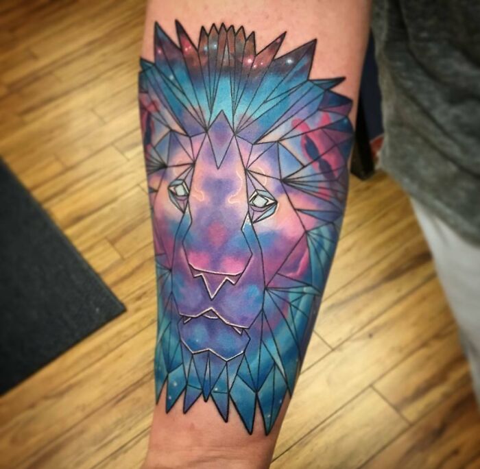 Geometric lion tattoo on forearm in vibrant colors, showcasing creativity and artistic detail.