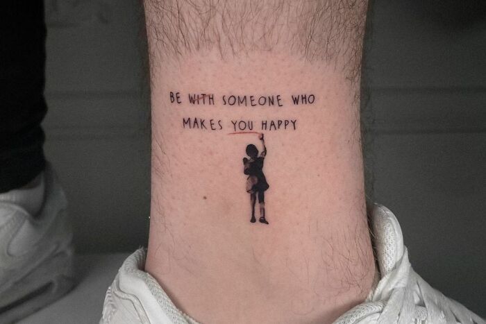 Self-love tattoo on leg with inspirational text and small figure reaching upwards.