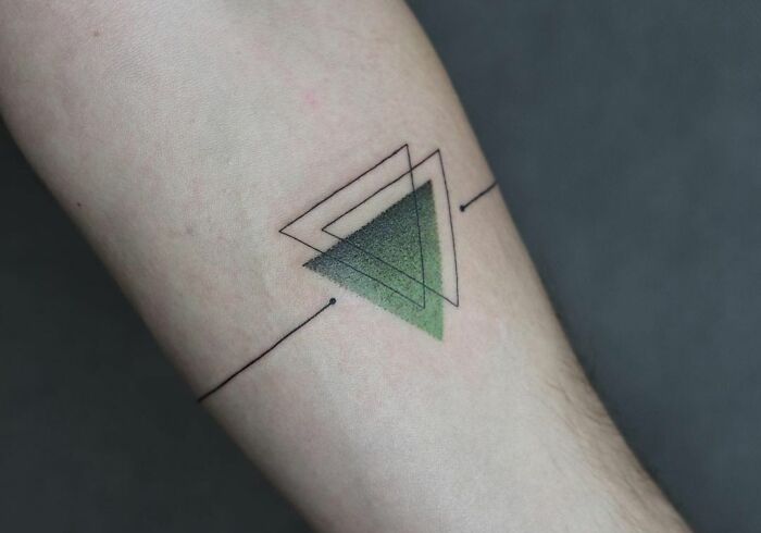 Geometric tattoo featuring layered triangles with gradient green shading on forearm.
