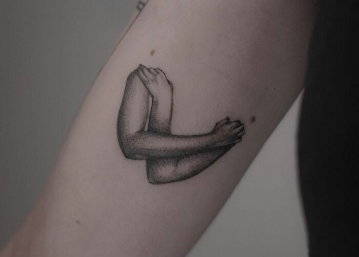 Self-love tattoo of arms hugging on the inner forearm, symbolizing self-care and appreciation.