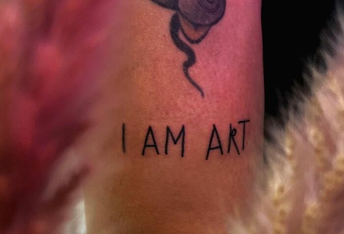 Close-up of a tattoo reading "I AM ART," showcasing self-love tattoo ideas.