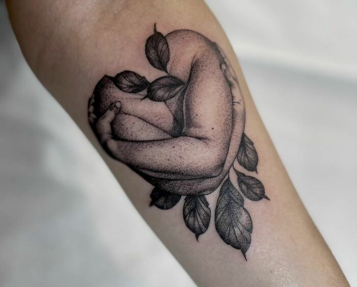 Tattoo of an embracing arm intertwined with leaves, symbolizing self-love and empowerment on the forearm.