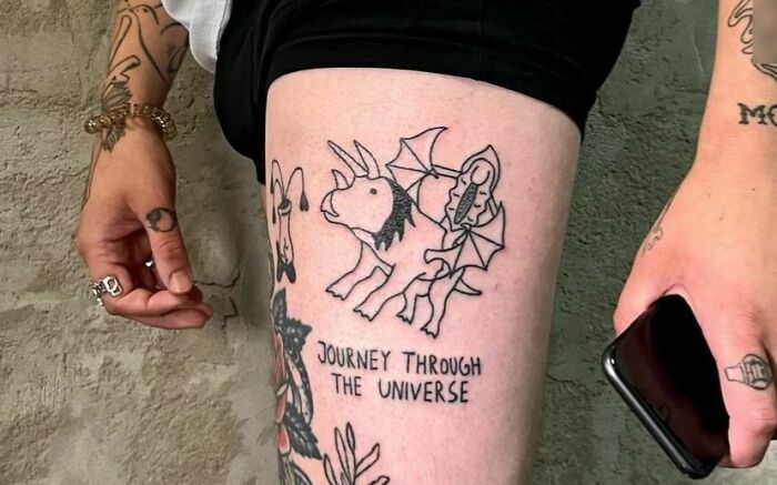 Self-love tattoo featuring a mystical creature with the phrase "Journey Through The Universe" on a person's thigh.