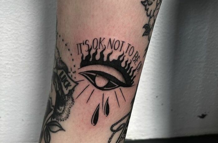 Self-love tattoo design with an eye and the phrase "It's OK not to be OK," emphasizing positive mental health.