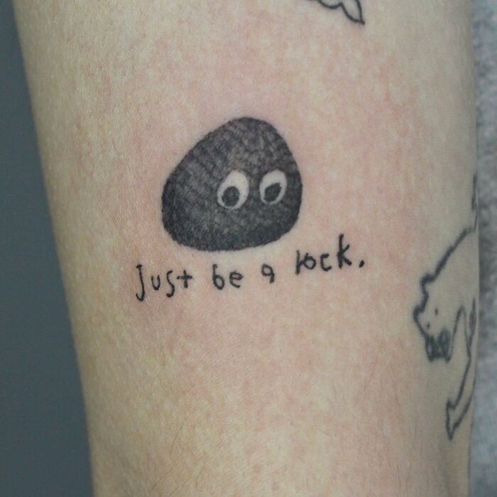 Self-love tattoo with a cute rock and the phrase "Just be a rock" on skin.