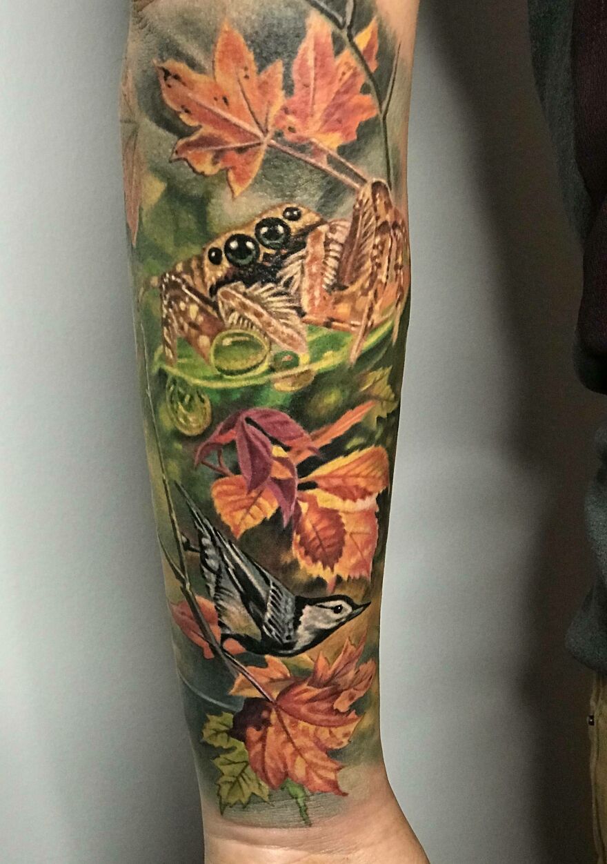 Arm tattoo featuring a realistic nuthatch and autumn leaves, showcasing detailed tattoo artistry.