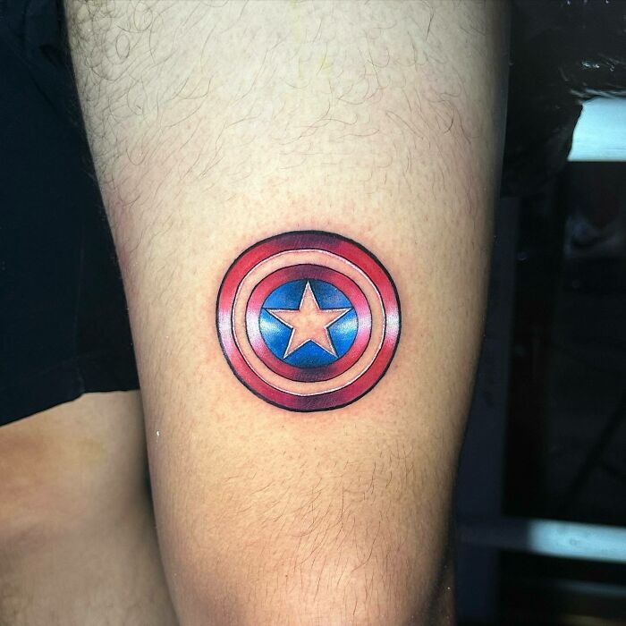 Captain America shield tattoo on arm, showcasing Marvel art.