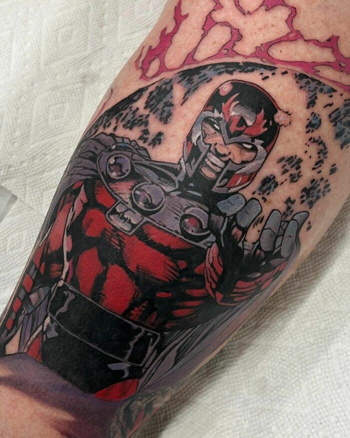 Marvel tattoo featuring a detailed red and black superhero in dynamic pose on forearm.