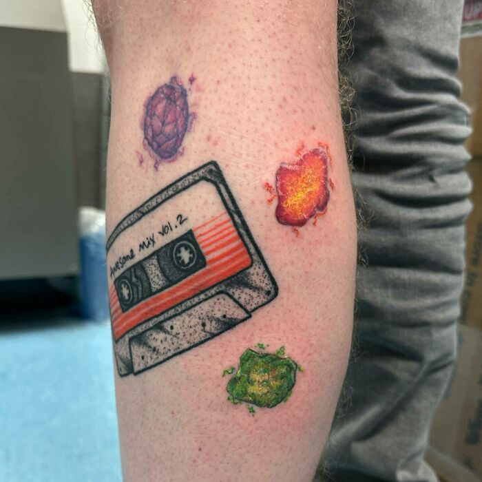 Marvel tattoos on a leg featuring a cassette tape and colorful cosmic designs.